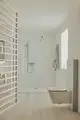 Helle, minimalistische Badezimmeransicht mit einer Glasdusche, einer Handbrause, einem wandmontierten WC und Holzfußboden. Ideal Standard Produkte sind sichtbar.